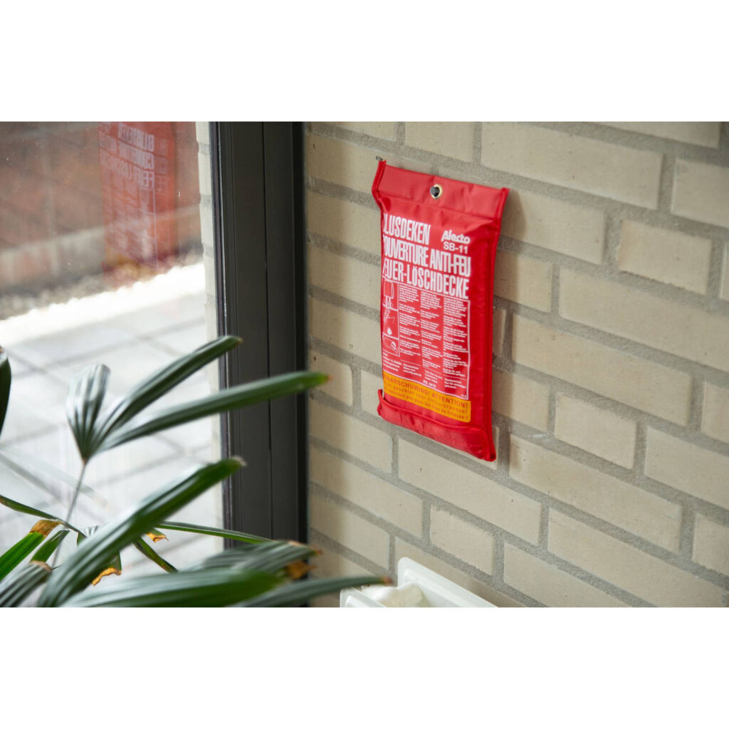 Een bakstenen muur waar een rode blusdeken tegen bevestigd is