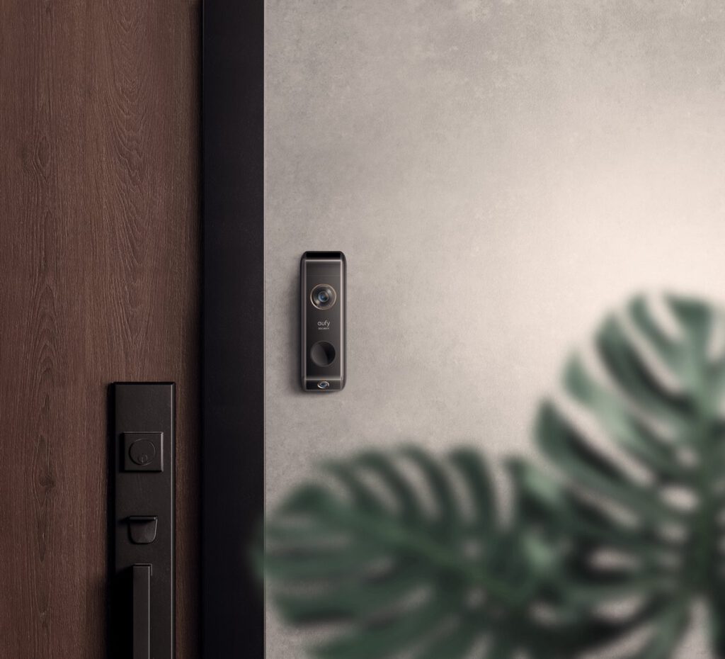 Een houten voordeur met daarnaast een witte muur met Eufy deurbel.