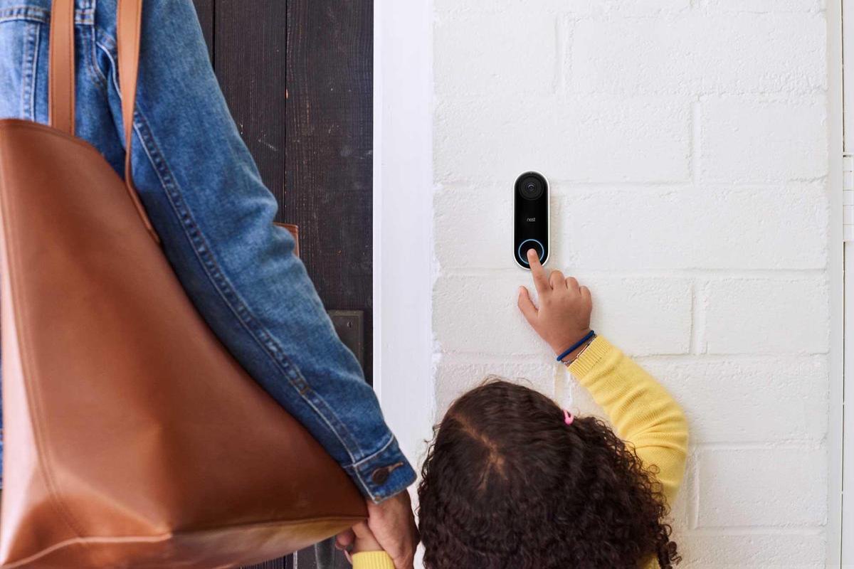 Een klein meisje die het knopje van een Google Nest deurbel indrukt.