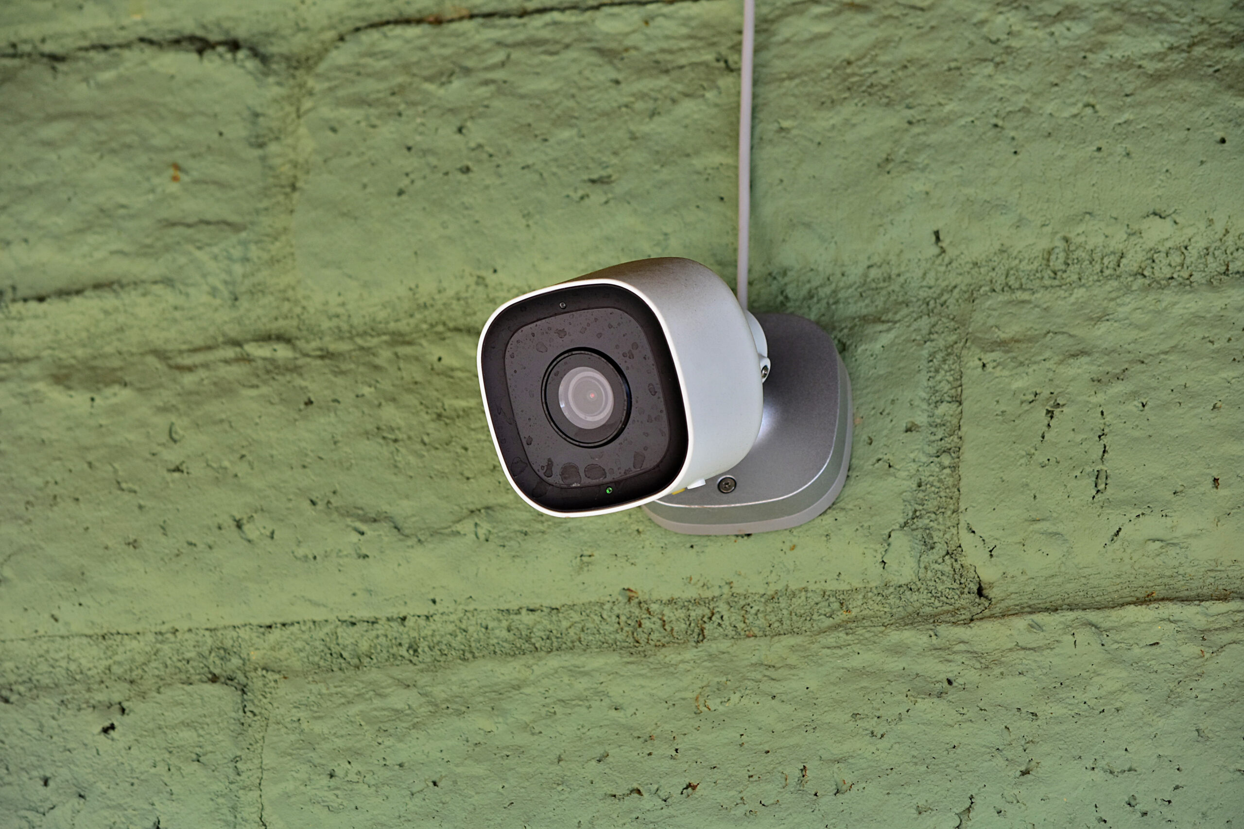 A home security camera is mounted on an outside wall.