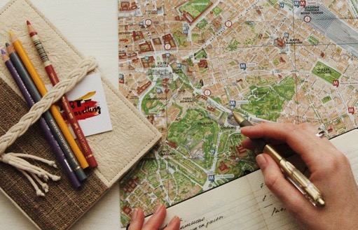 Person's hand with a pen looking at a map to plan a route
